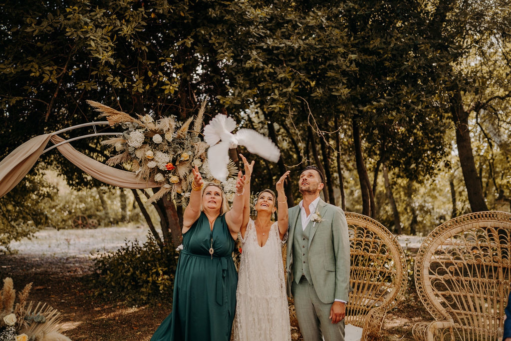 Plan large d'une cérémonie de lacher de colombe. On y voit l'officiante qui lâche la colome devant les mariés